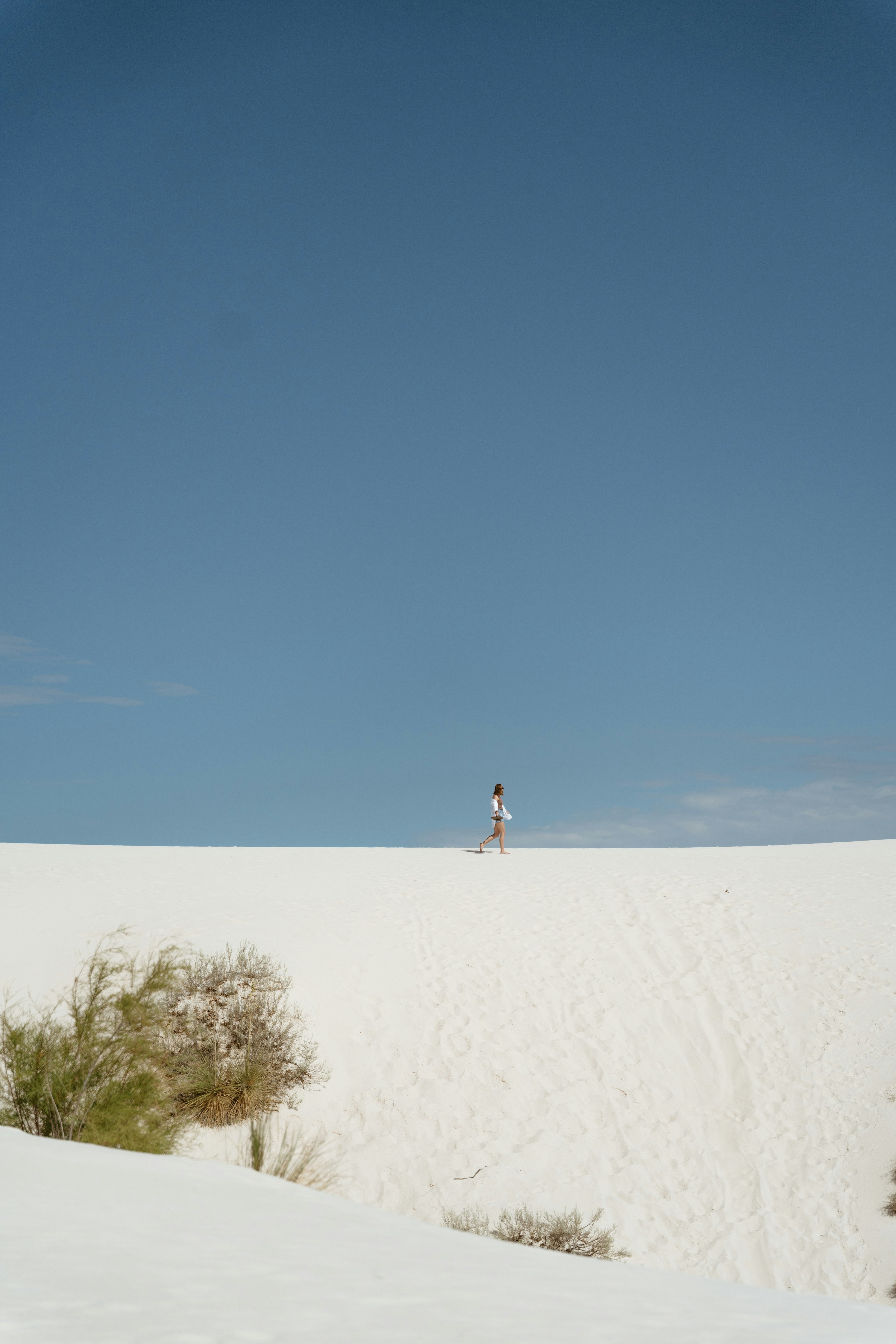 person in white shirt walking on sand during daytime